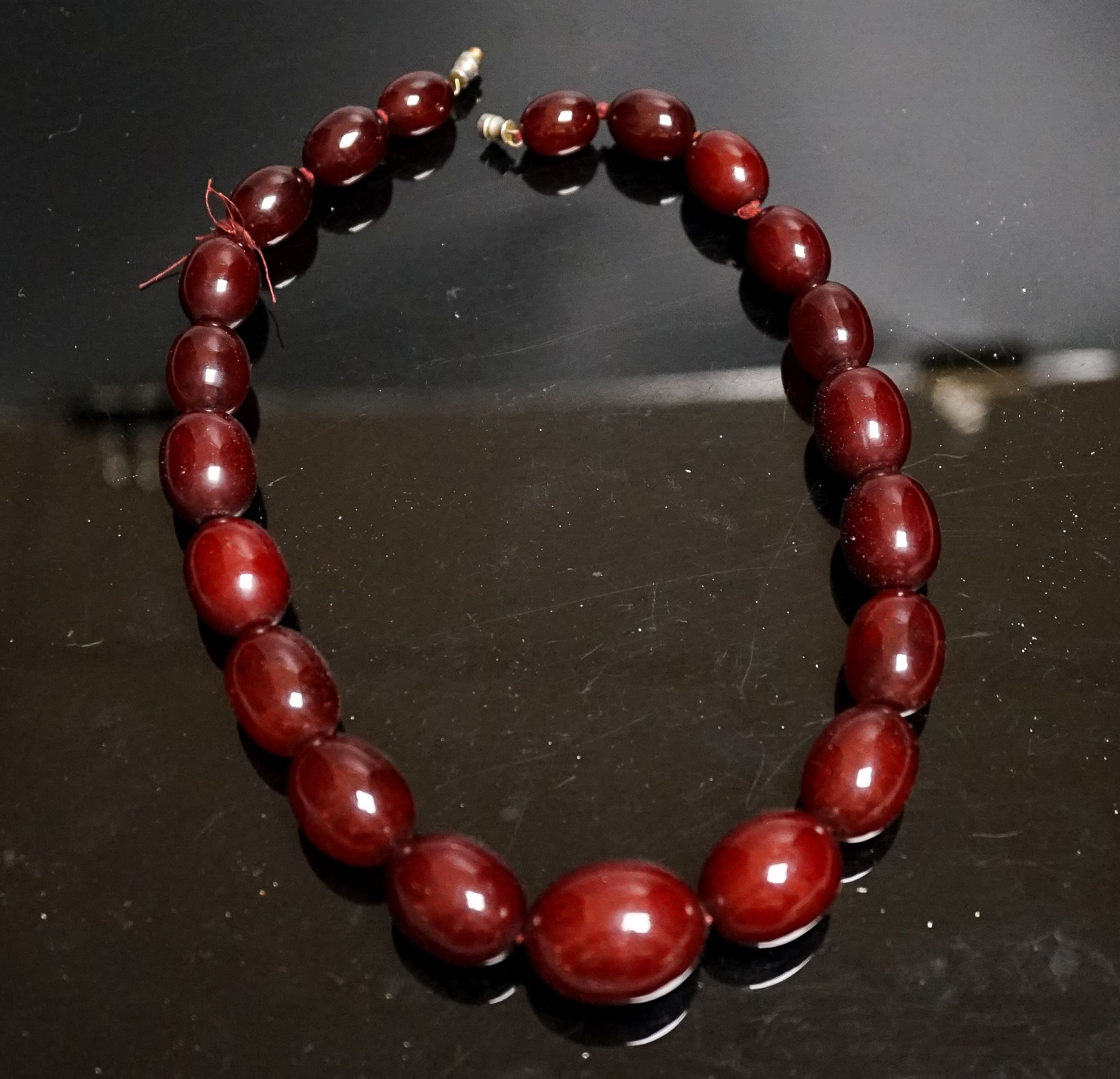 A single strand graduated simulated cherry amber oval bead necklace, 44cm, gross weight 78 grams.